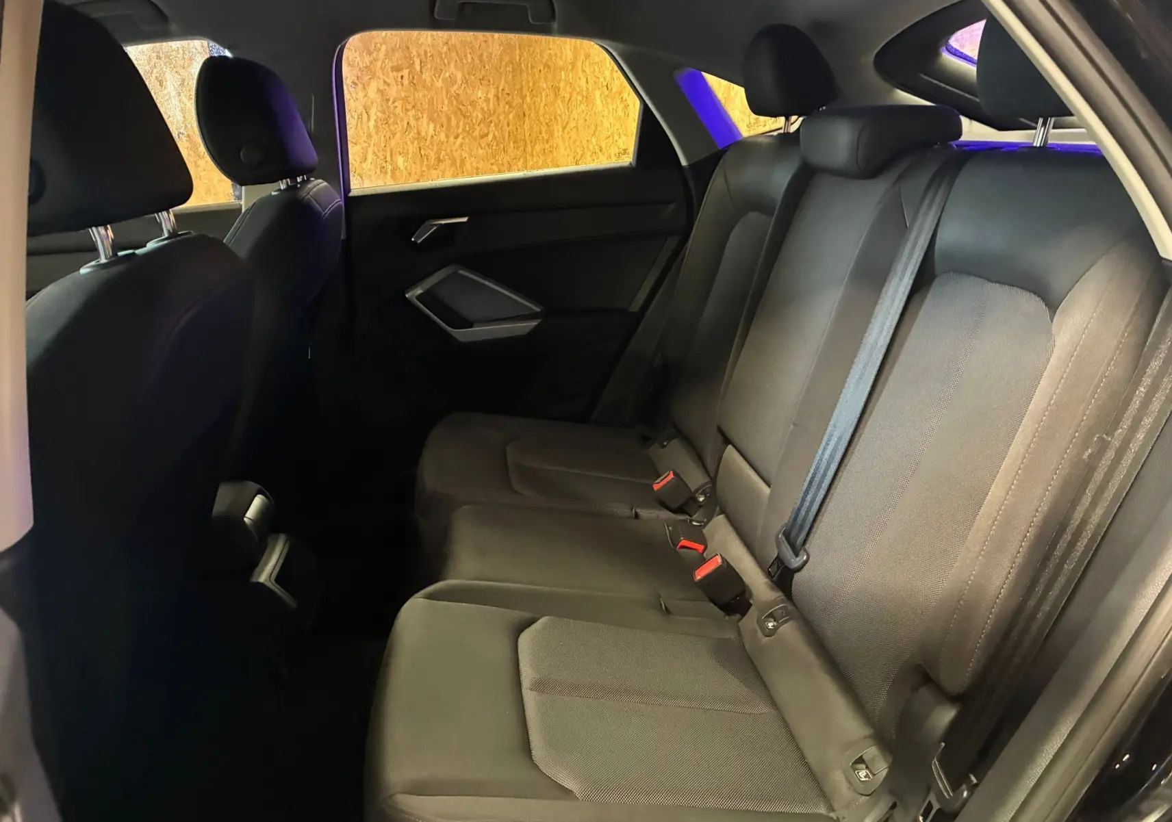 Vue intérieure arrière côté droit de l'Audi Q3 Sportback noir, montrant les sièges arrière en tissu et cuir avec ceintures de sécurité.
