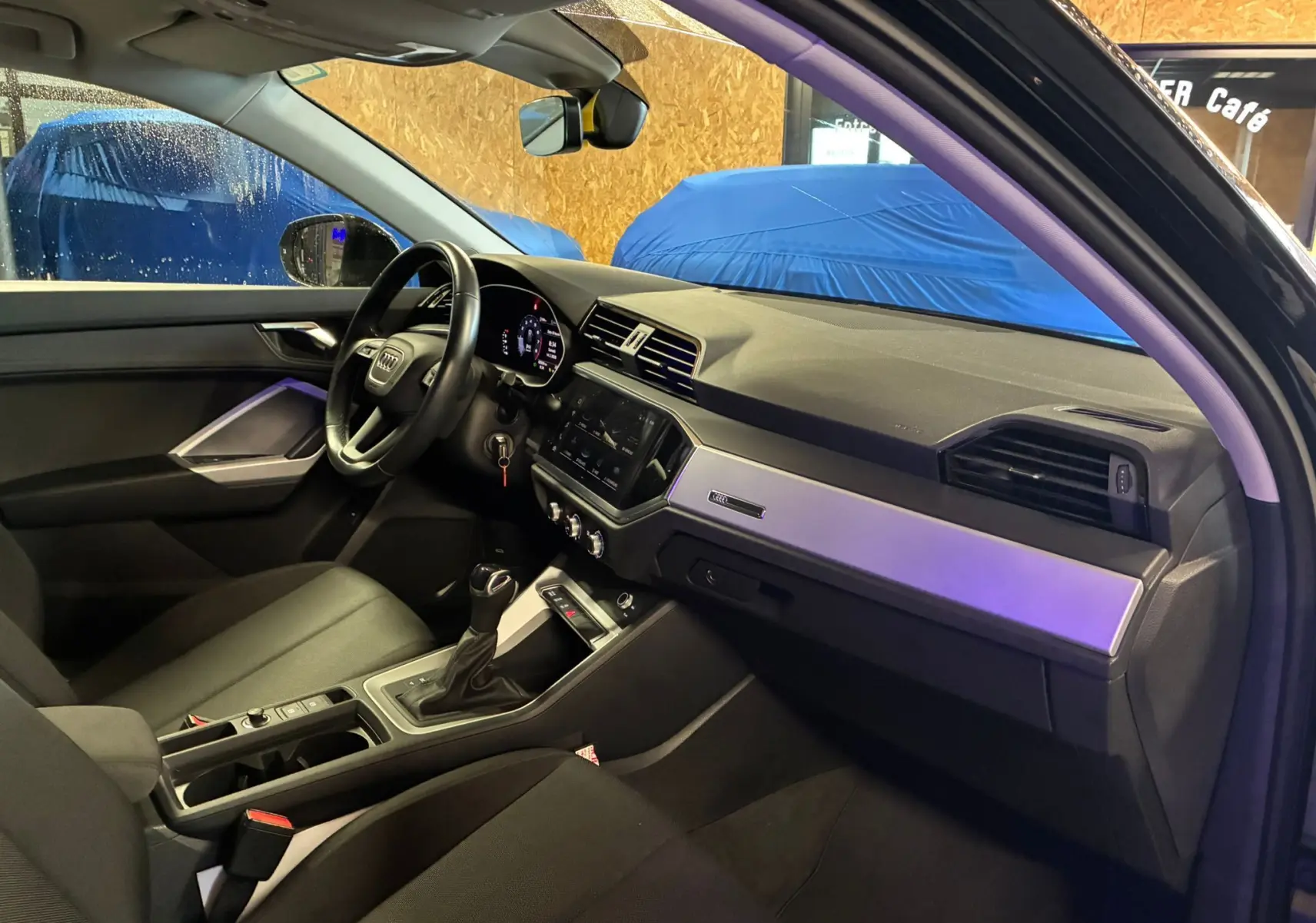 Intérieur noir de l'Audi Q3 Sportback 2022 vu côté conducteur, avec tableau de bord moderne et écran tactile central.