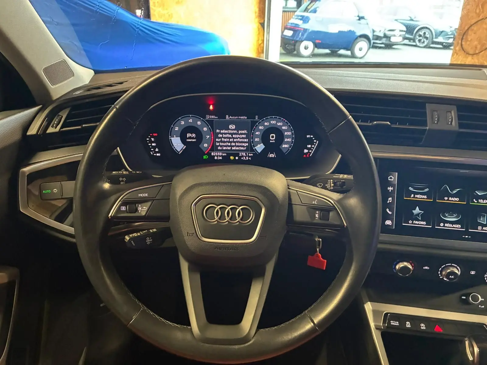 Vue intérieure centrée sur le volant cuir multifonctions d'un Audi Q3 Sportback 2022 avec tableau de bord numérique et écran tactile.