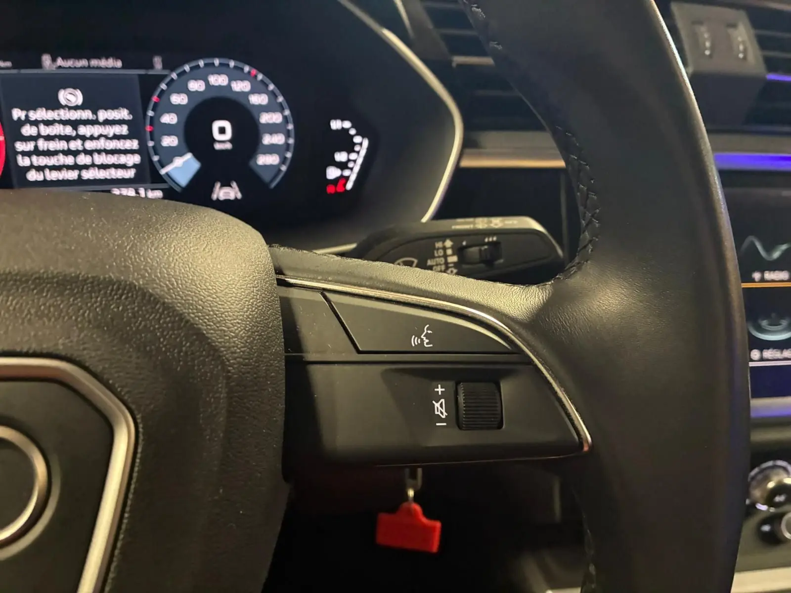 Gros plan sur le volant cuir multifonctions noir de l'Audi Q3 Sportback 2022 avec tableau de bord digital en arrière-plan.