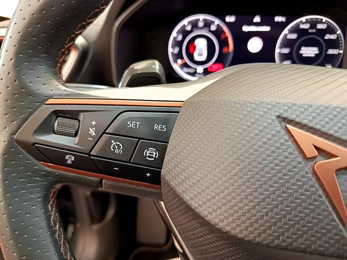 Gros plan sur le volant cuir et alu de la CUPRA Formentor 1.5 TSI 2022, avec commandes multifonctions et logo cuivré.