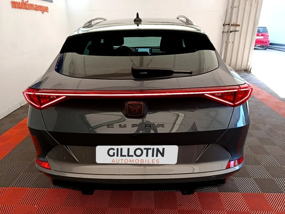 Vue arrière d'une CUPRA Formentor gris foncé avec feux LED reliés et logo central lumineux.