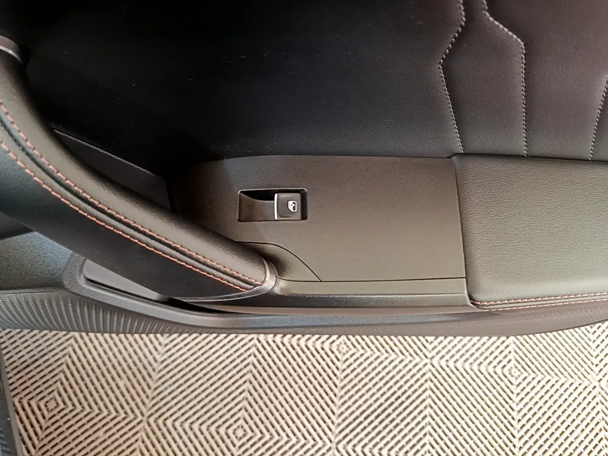 Détail de la porte intérieure côté gauche de la CUPRA Formentor gris foncé avec bouton de verrouillage et surpiqûres rouges.