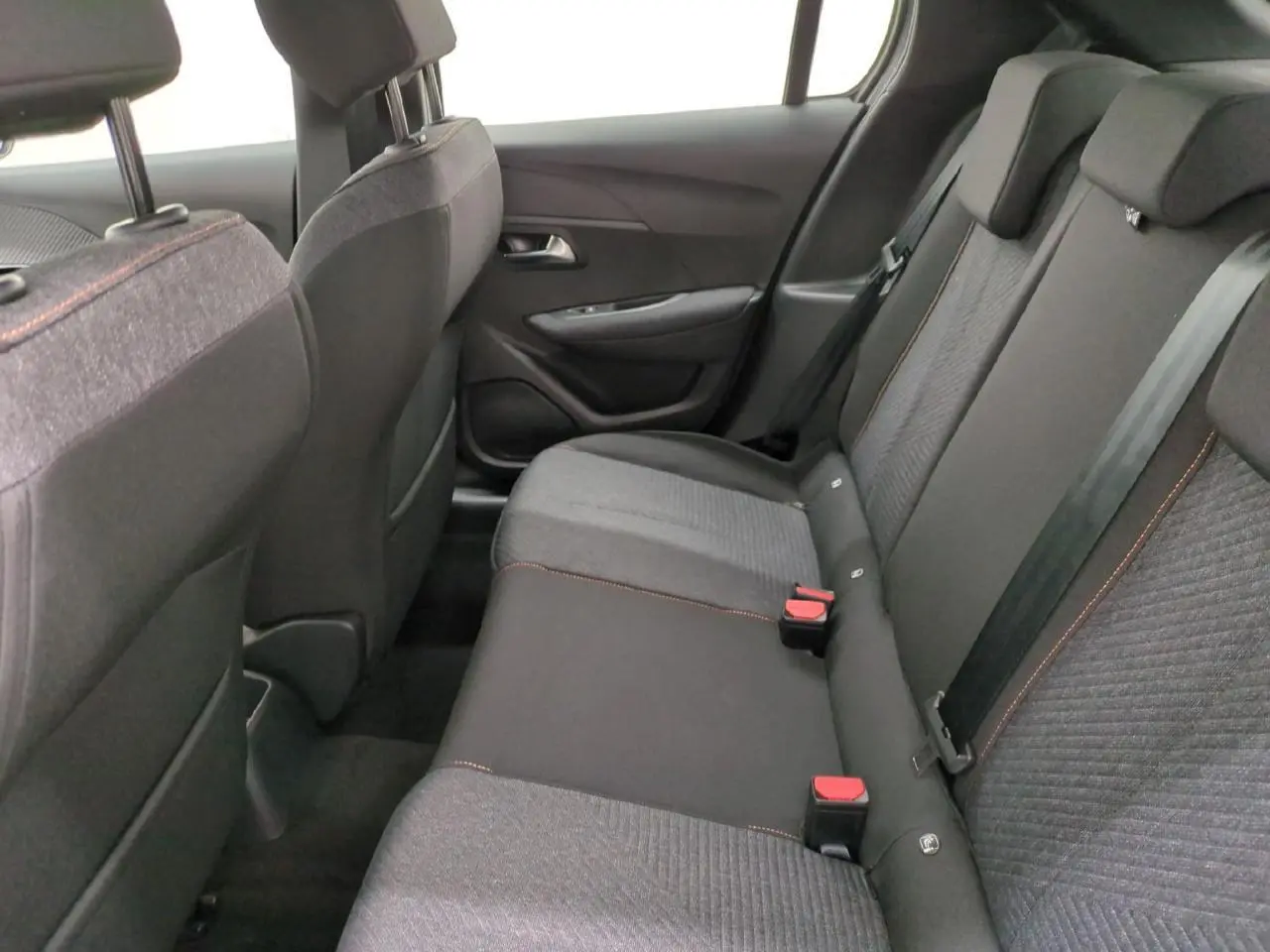 Vue intérieure côté droit sur la banquette arrière gris foncé avec surpiqûres orange de la Peugeot 208 2025 Style Navigation.