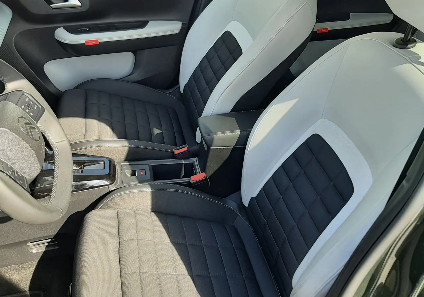 Vue intérieure côté conducteur du Citroën C3 Aircross 2025, sièges bi-ton noir et blanc avec surpiqûres apparentes.