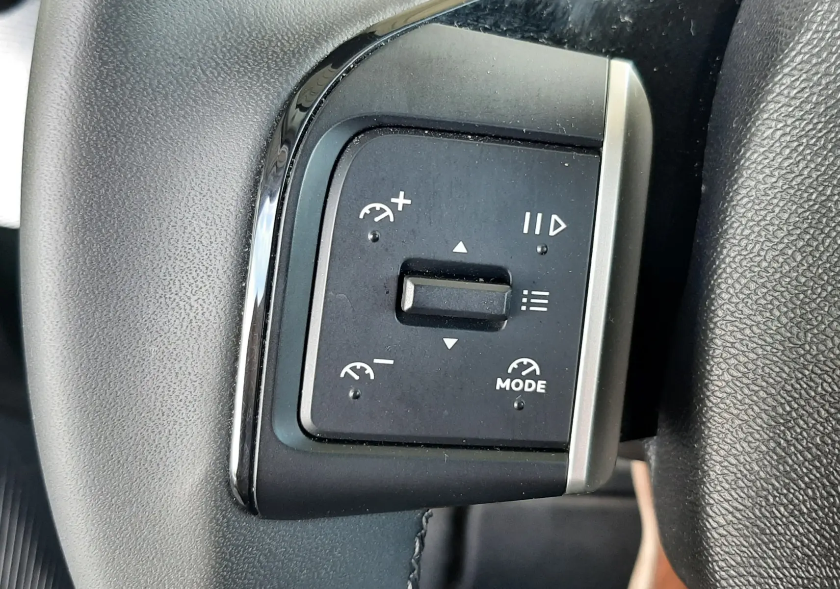 Gros plan sur les commandes de régulateur de vitesse au volant du Citroën C3 Aircross 2025, intérieur noir.