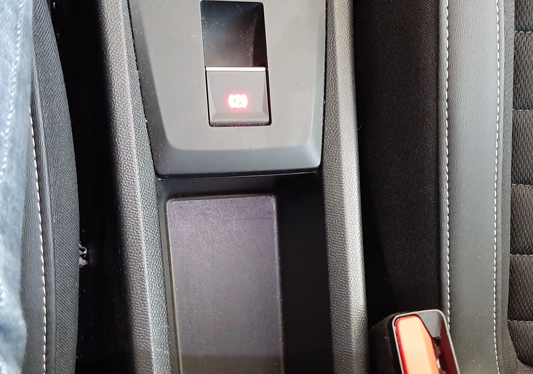 Gros plan sur la console centrale noire du Citroën C3 Aircross avec frein à main électronique et ceintures rouges.