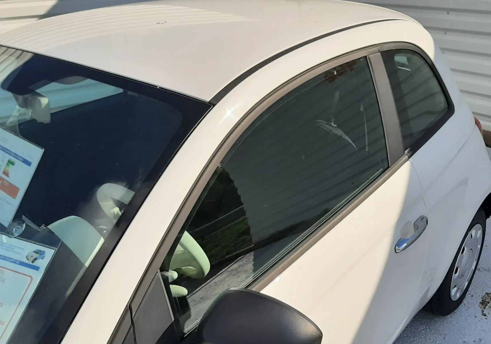 Vue de profil côté gauche d'une FIAT 500 blanche 2023 avec rétroviseur noir et carrosserie compacte.