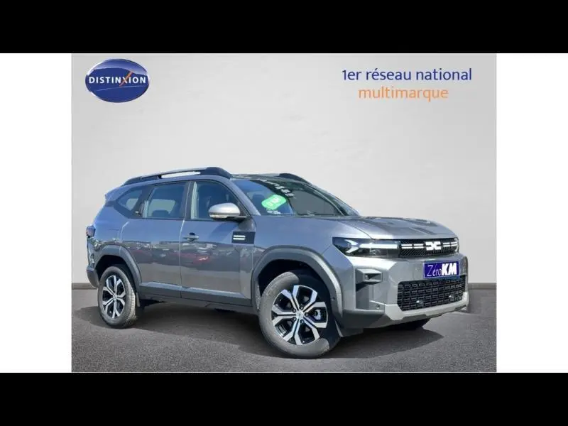 Vue 3/4 avant droite du SUV Dacia Bigster gris métallisé avec jantes alu et barres de toit sur fond neutre.