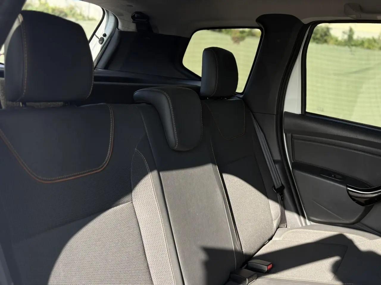 Vue côté droit des sièges arrière en cuir et tissu noir du Dacia Duster blanc Glacier 2017 avec appuie-têtes réglables.