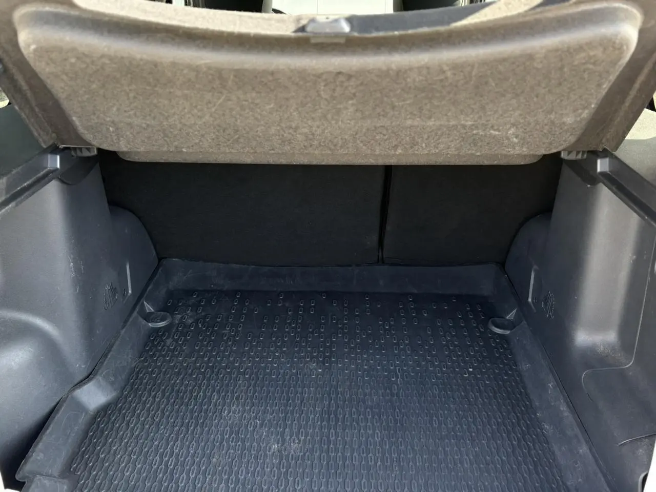 Coffre ouvert d'un Dacia Duster blanc glacier, montrant la surface de chargement avec tapis en caoutchouc noir.