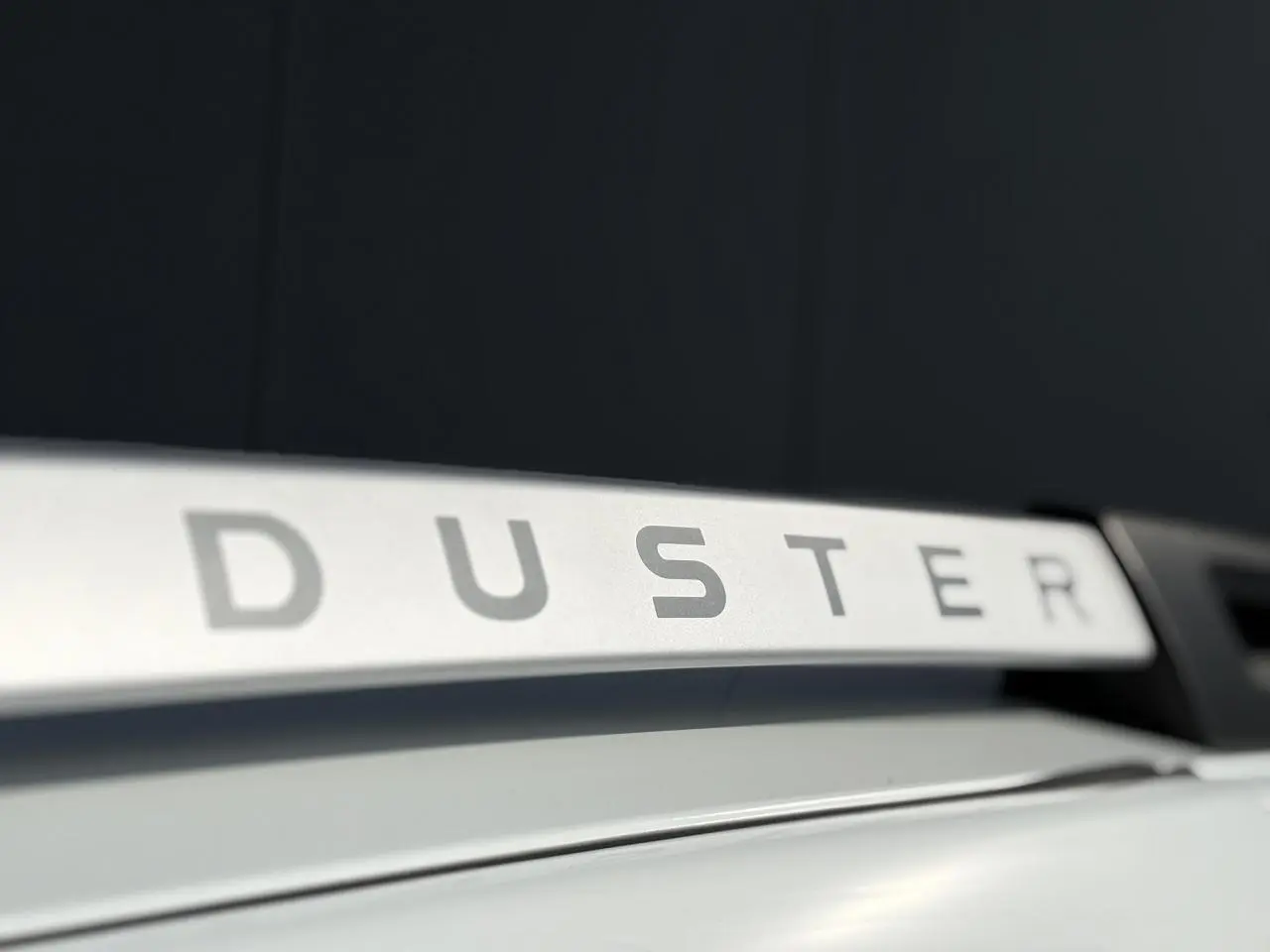 Gros plan sur la barre de toit blanche du Dacia Duster 2017 avec lettrage DUSTER visible en relief.