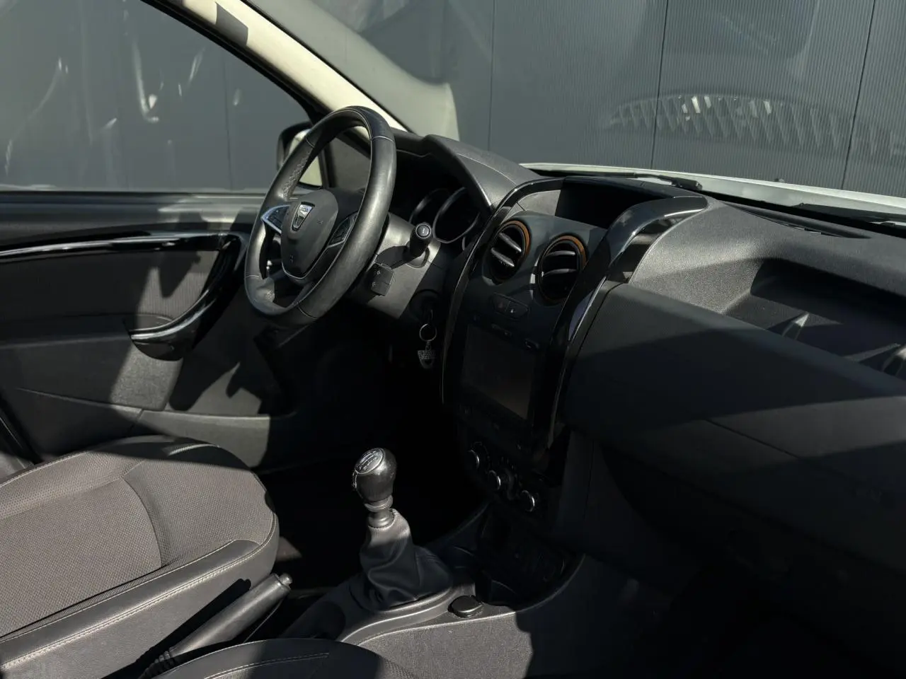 Intérieur du Dacia Duster TCE 125 Explorer 2017, vue côté conducteur, volant cuir et levier de vitesse manuel visibles.