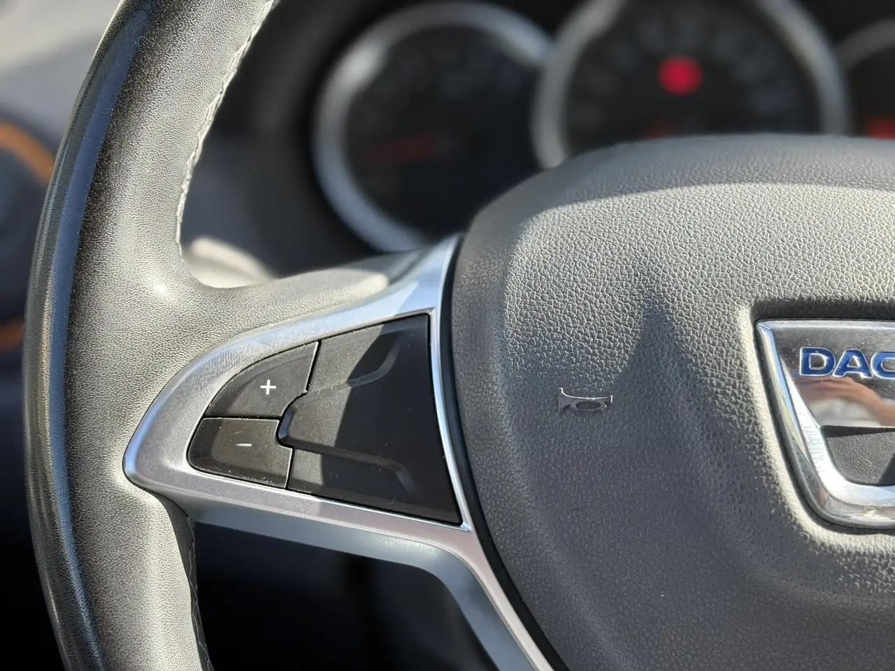 Gros plan sur le volant en cuir du Dacia Duster 2017, montrant les commandes de régulateur de vitesse à gauche.