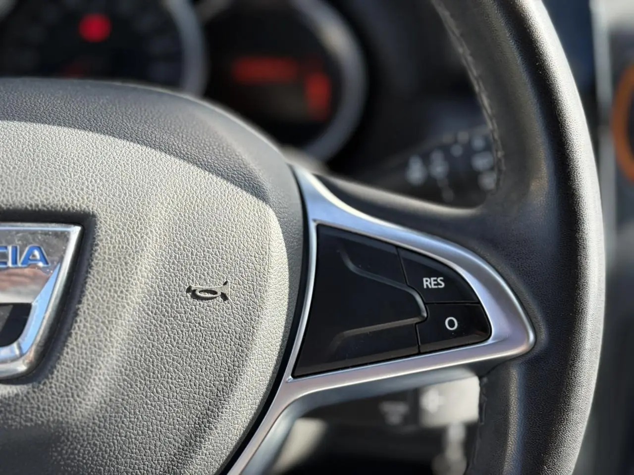 Gros plan sur le volant en cuir du Dacia Duster TCE 125 Explorer, avec commandes multifonctions visibles.