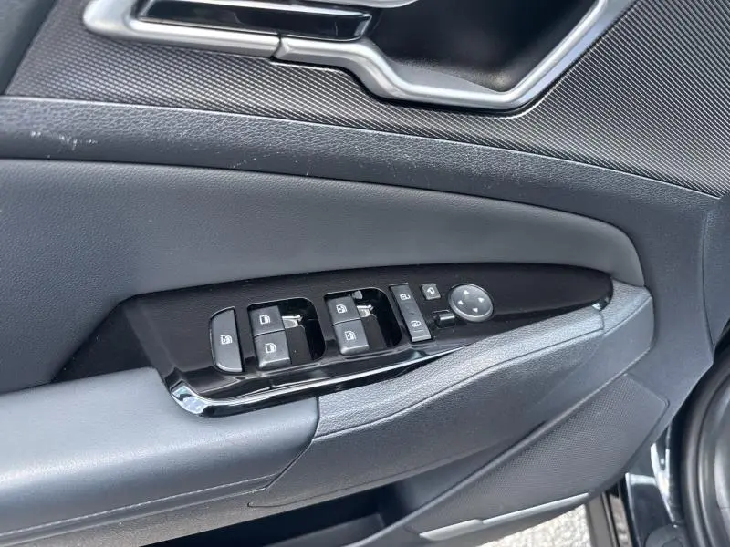 Gros plan sur la commande des vitres et rétroviseurs côté conducteur du KIA SPORTAGE noir Basalte métallisé 2022.