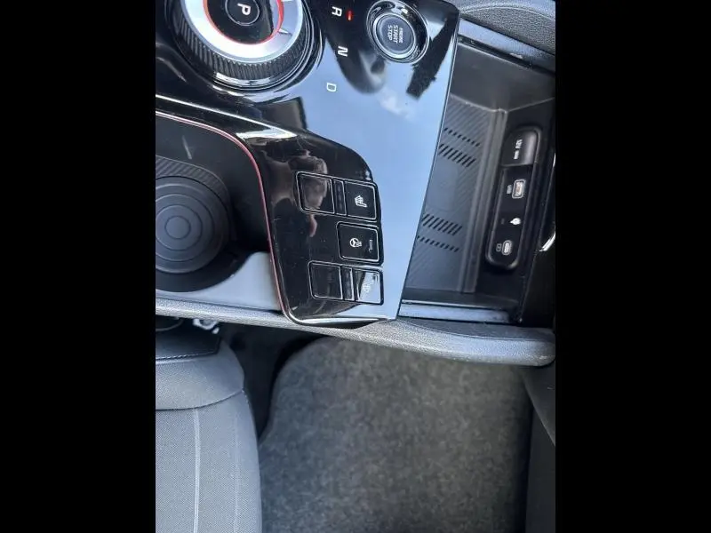 Gros plan sur la console centrale noire brillante du Kia Sportage 2022 avec commandes de sièges chauffants et prise USB visible.
