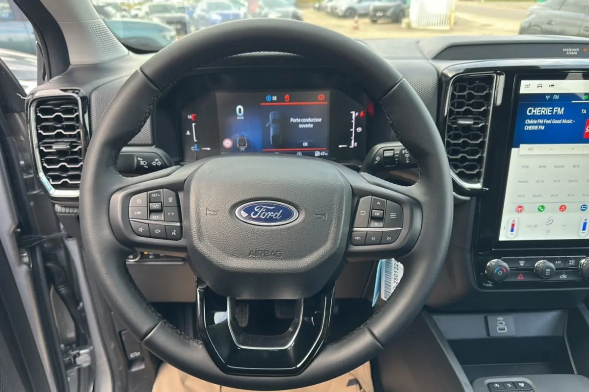 Vue rapprochée du volant cuir multifonctions noir et du tableau de bord digital du Ford Ranger gris iconic 2026.