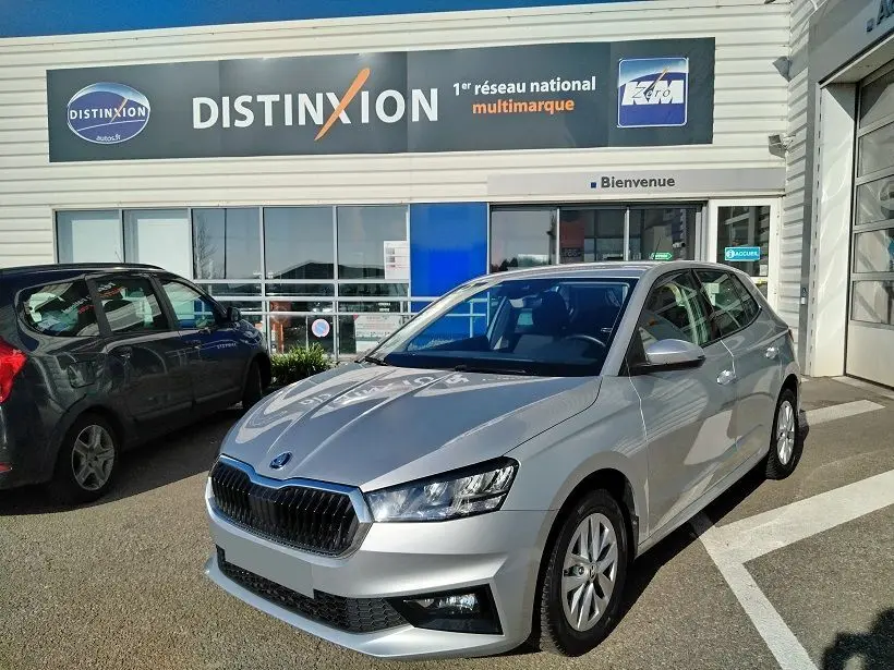 Vue 3/4 avant droite d'une Skoda Fabia blanche 2023, stationnée devant un concessionnaire Distinxion.