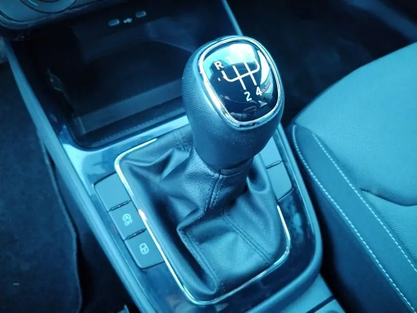 Gros plan sur le levier de vitesse manuel noir de la Skoda Fabia 2023, avec sellerie tissu gris visible à droite.