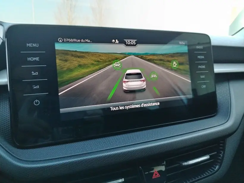 Écran central montrant l’assistance de conduite avec une Skoda Fabia blanche vue de l’arrière sur une route droite.