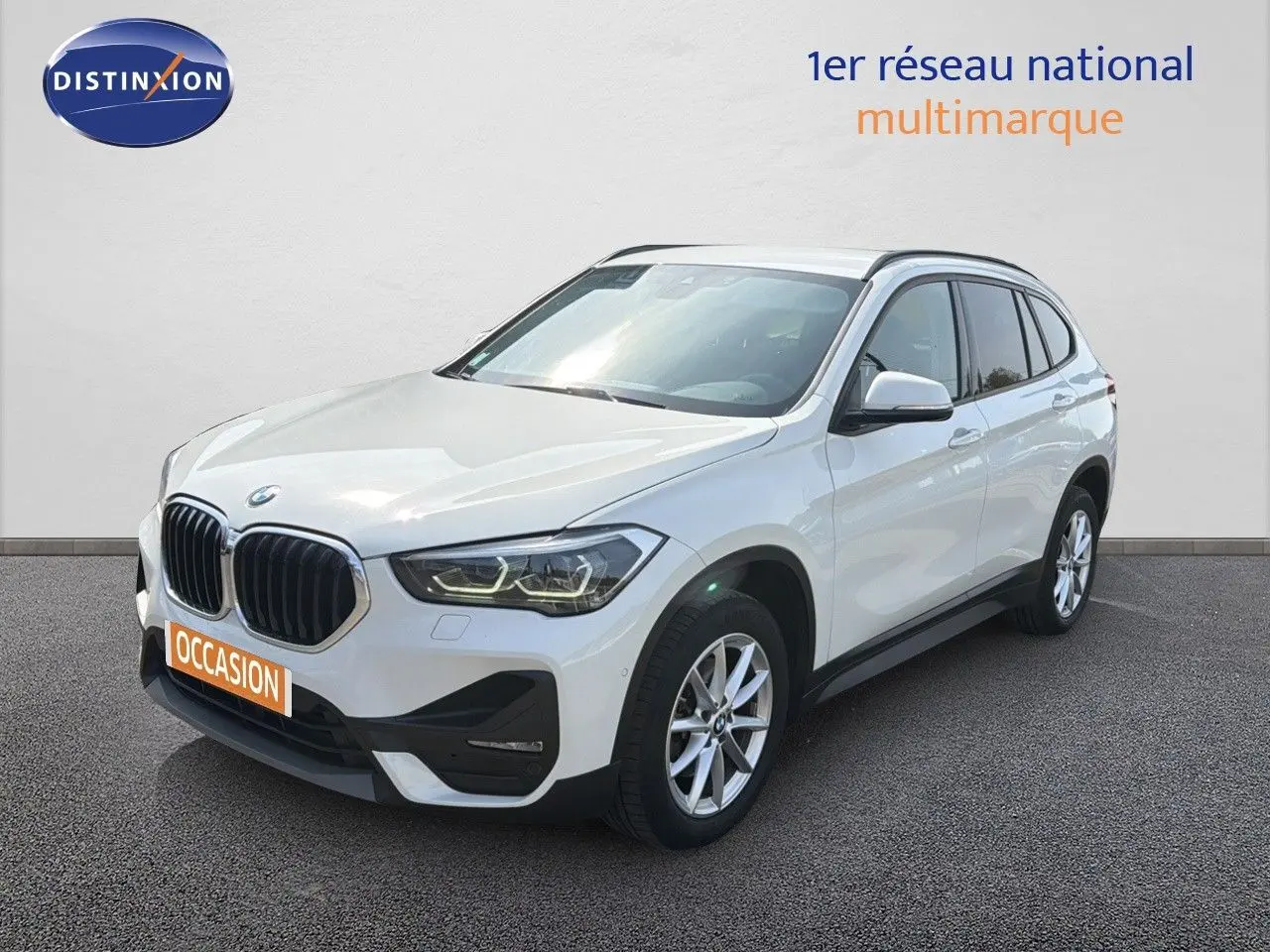 BMW X1 blanc vue 3/4 avant droit, avec calandre noire et jantes alliage 17 pouces visibles.