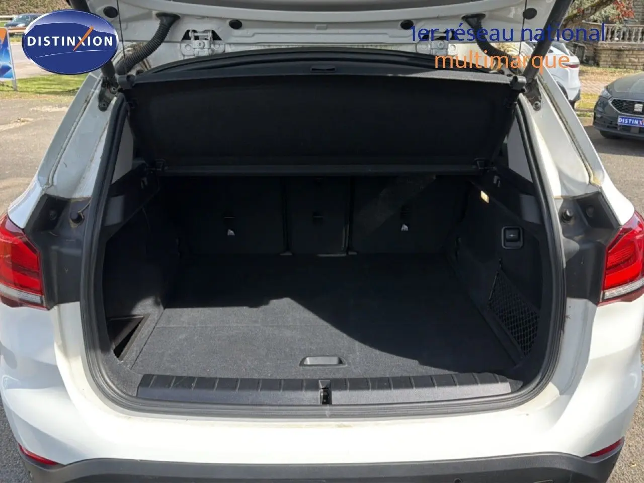 Coffre ouvert vu de l'arrière d'un BMW X1 blanc, montrant un espace de chargement spacieux et propre.