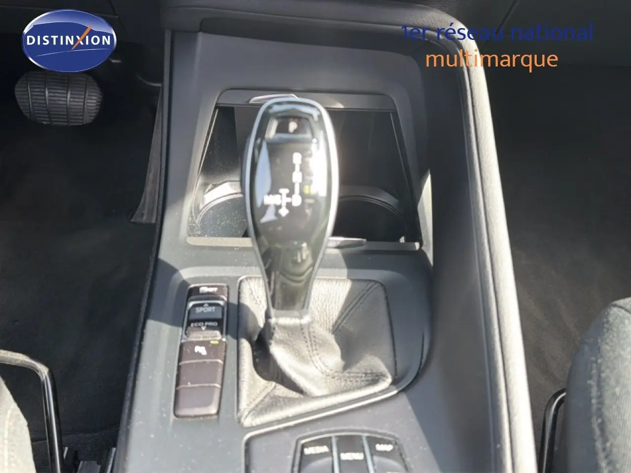 Gros plan sur le levier de vitesse automatique et les commandes de mode de conduite dans l’habitacle d’une BMW X1 blanche.