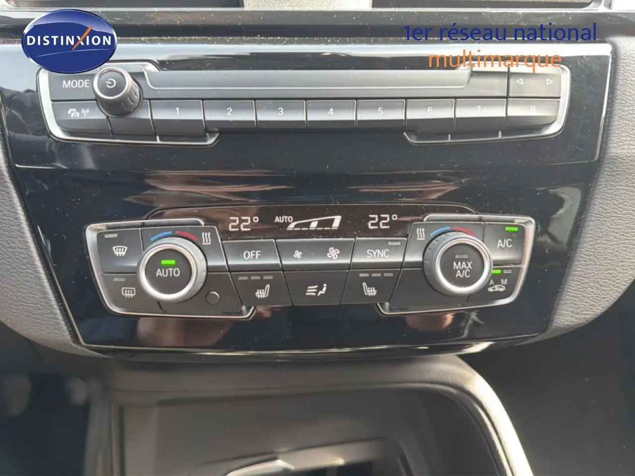 Tableau de bord de BMW X1 2022 en gros plan, montrant les commandes de climatisation automatique et les boutons multifonctions.