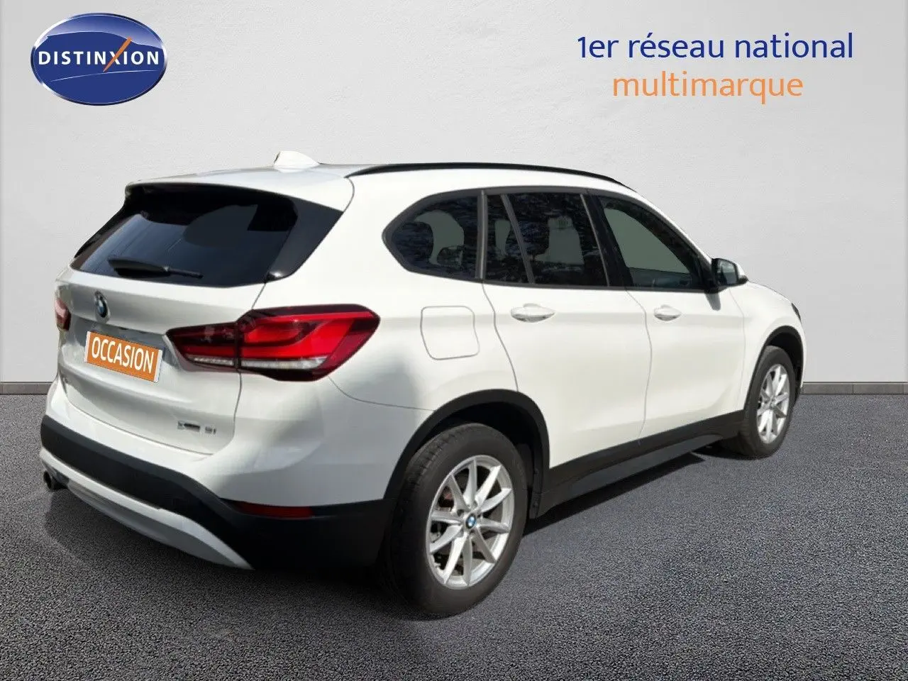 BMW X1 blanc vue 3/4 arrière côté droit, avec jantes alliage et feux arrière LED distinctifs.