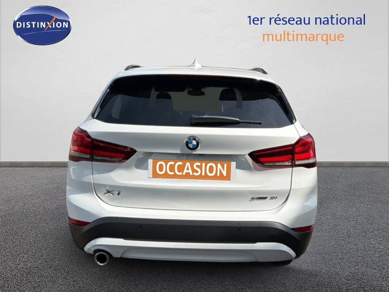 Vue arrière d'un BMW X1 blanc avec feux rouges et plaque "OCCASION" sur fond neutre.