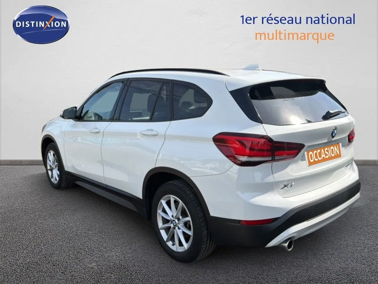BMW X1 blanc vue 3/4 arrière côté gauche, avec feux arrière rouges et jantes alliage argentées.
