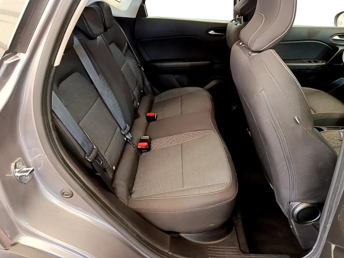 Vue intérieure côté arrière gauche du Renault Captur gris foncé, montrant la banquette arrière en tissu avec ceintures de sécurité.