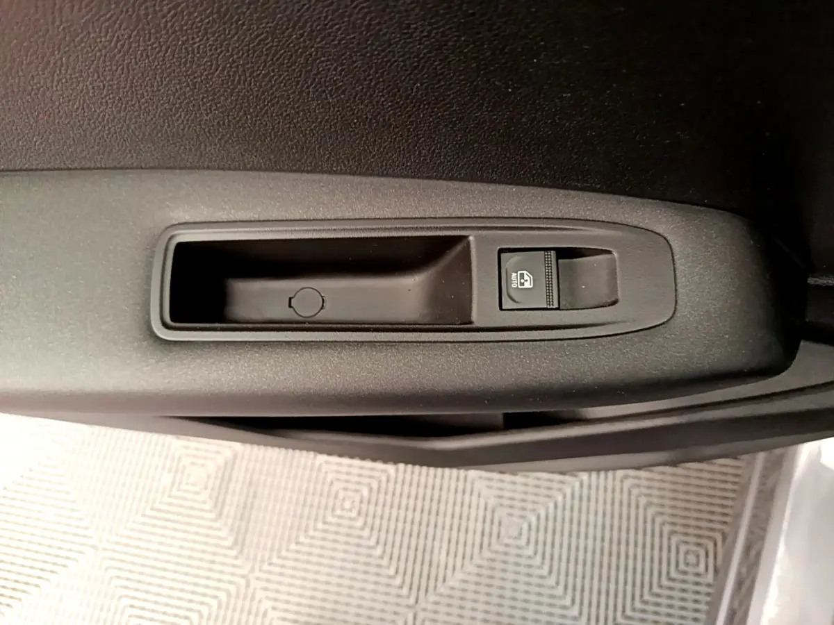 Gros plan sur le bouton de lève-vitre électrique côté conducteur du Renault Captur Zen E-Tech hybride gris foncé.