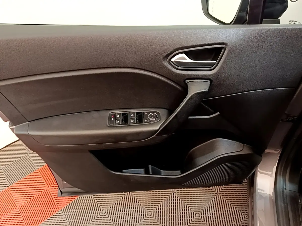 Gros plan sur la porte avant gauche gris foncé du Renault Captur Zen E-Tech hybride 2022 avec commandes de vitres et poignée intégrée.
