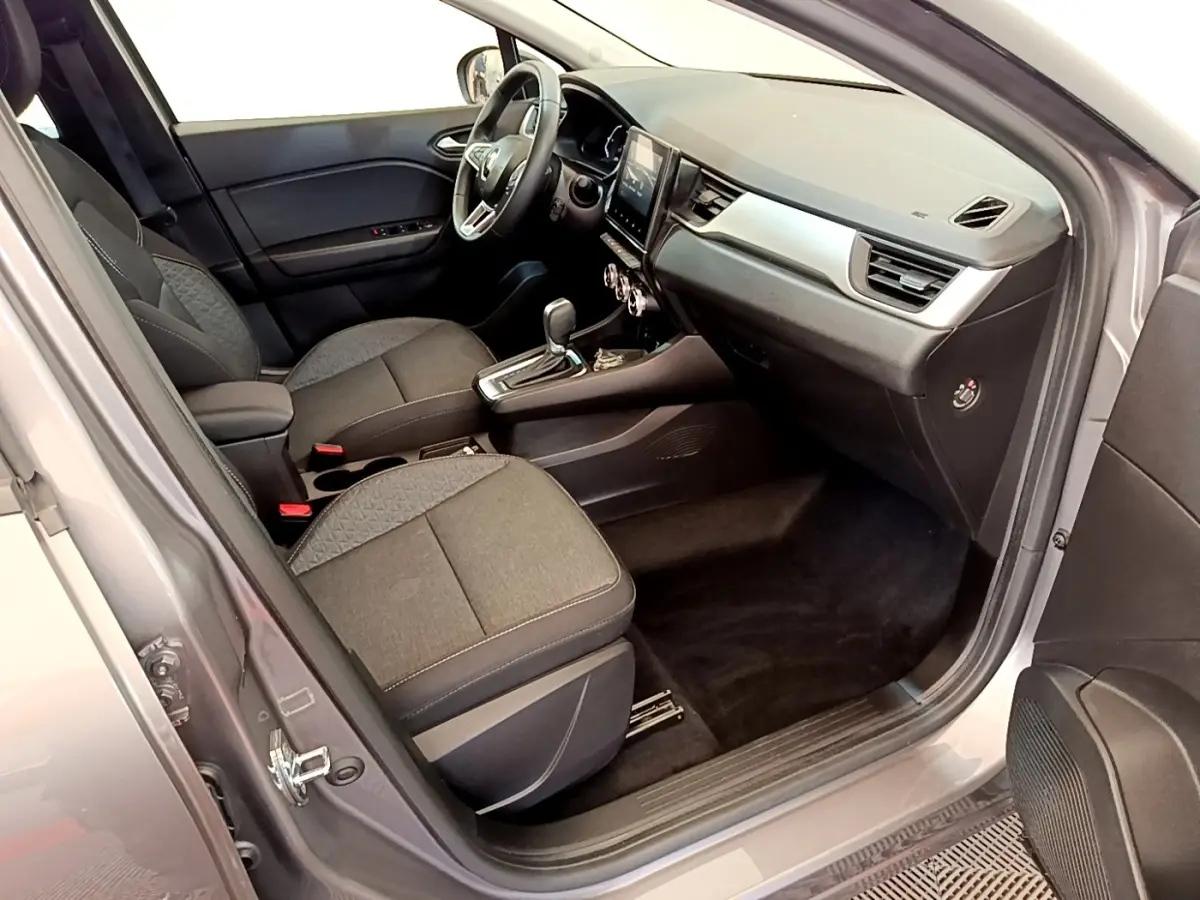 Intérieur avant droit du Renault Captur Zen E-Tech gris foncé, montrant sièges tissu et tableau de bord avec écran tactile.