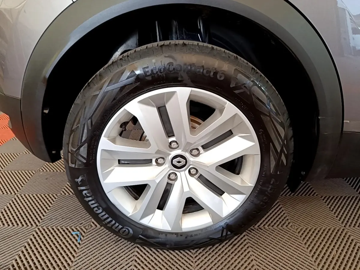 Gros plan sur la roue arrière gauche d’un Renault Captur gris foncé, mettant en valeur la jante et l’arche de roue noire.