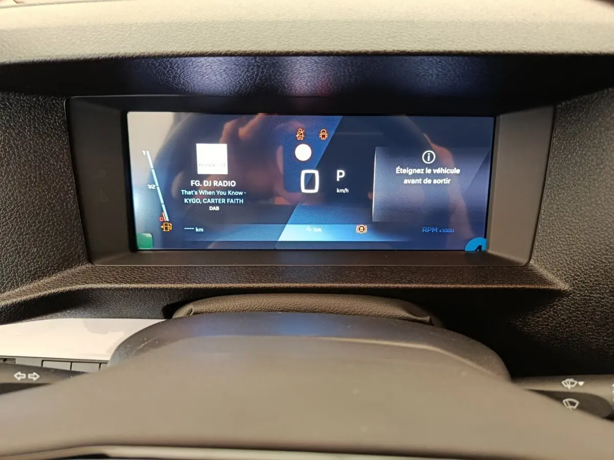 Vue rapprochée du tableau de bord numérique du Peugeot Expert Fourgon XL noir, affichant la radio et les alertes.