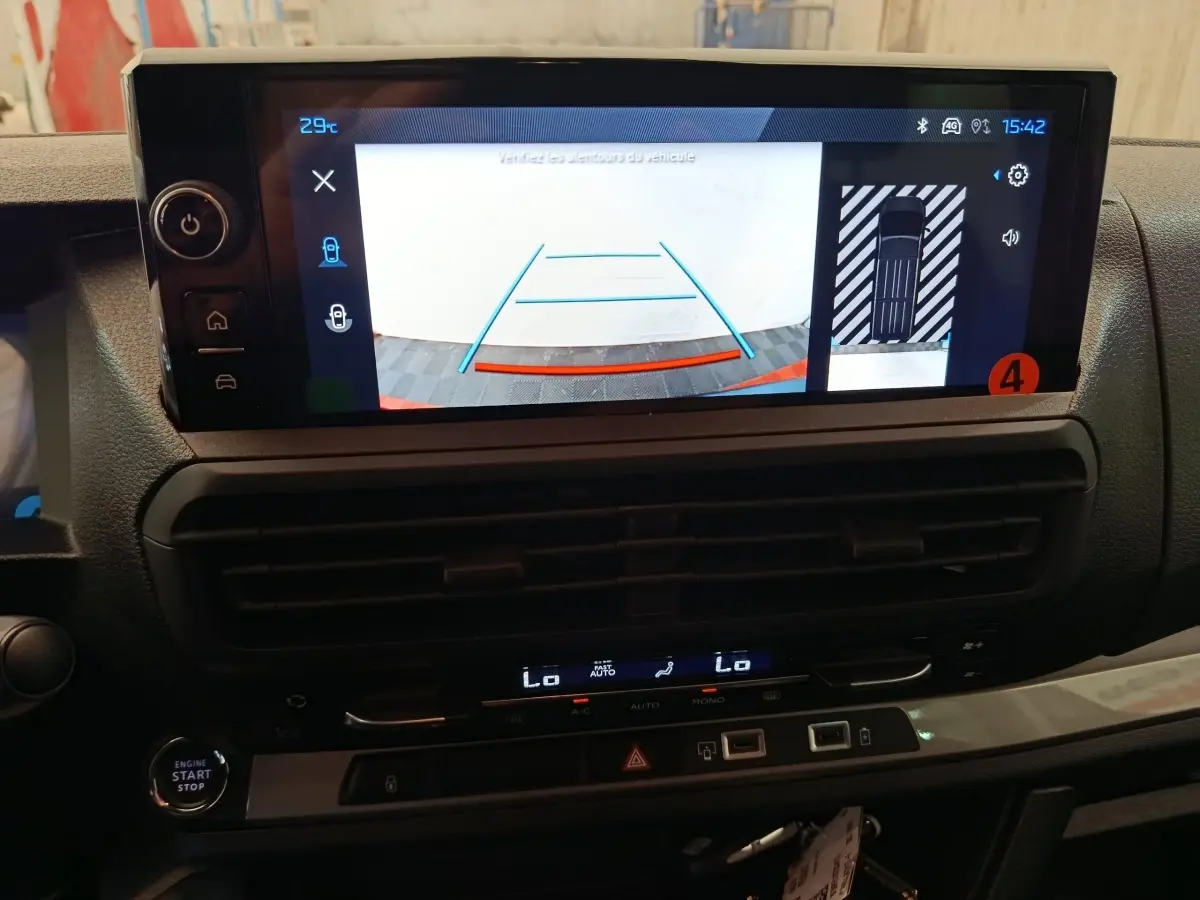 Vue rapprochée de l’écran tactile du tableau de bord du Peugeot Expert Fourgon XL noir, affichant la caméra de recul et l’aide au stationnement.
