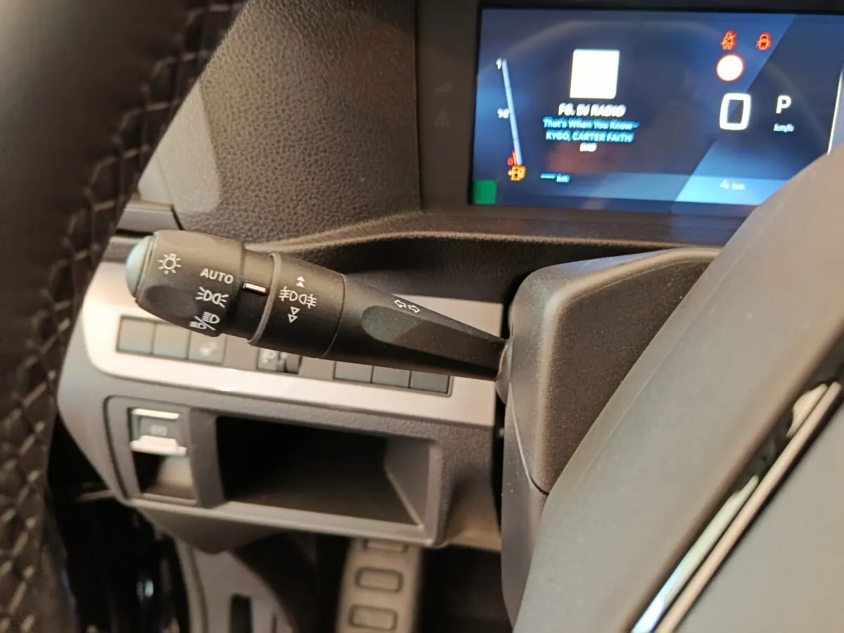 Gros plan sur la manette des feux et clignotants du Peugeot Expert Fourgon noir, avec tableau de bord numérique en arrière-plan.