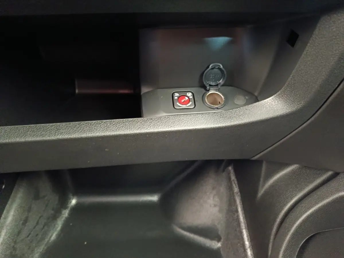Gros plan intérieur sur la prise 12V et le rangement sous le tableau de bord du Peugeot Expert Fourgon noir.