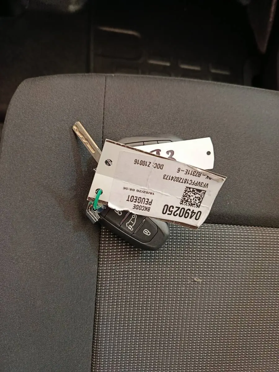 Clé de Peugeot Expert Fourgon XL Diesel noire posée sur un siège tissu gris à motifs.