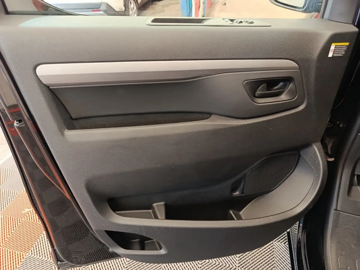 Vue rapprochée de la porte avant droite noire du Peugeot Expert Fourgon XL Diesel 2026 avec poignée et rangements intégrés.