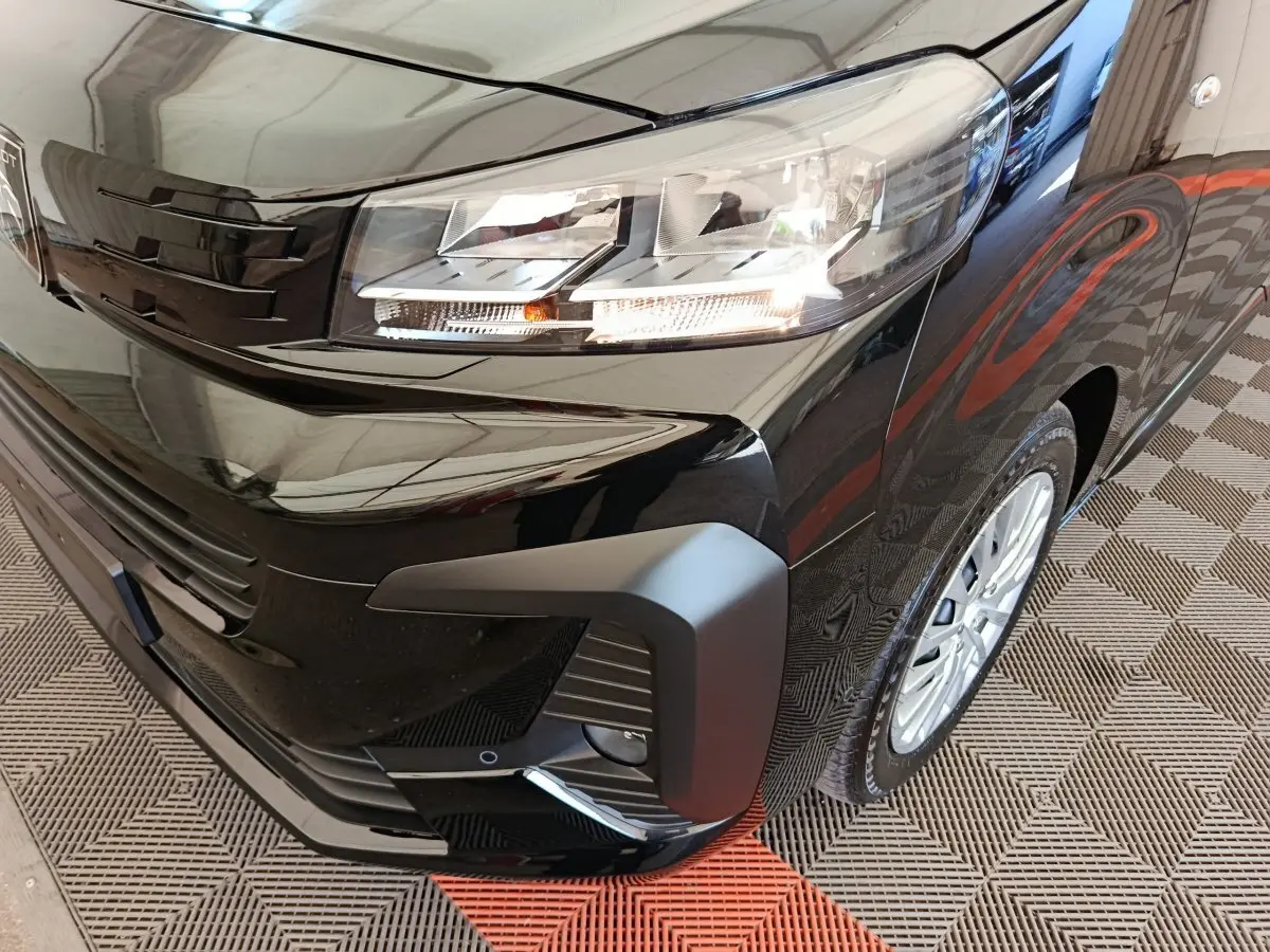 Gros plan sur l'avant droit noir brillant du Peugeot Expert Fourgon XL Diesel 2026 avec phares allumés et jante visible.