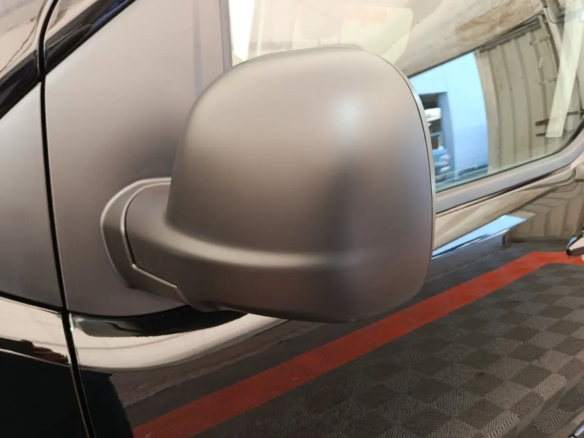 Gros plan sur le rétroviseur côté gauche du Peugeot Expert Fourgon XL noir, avec reflet de l’environnement sur la carrosserie.