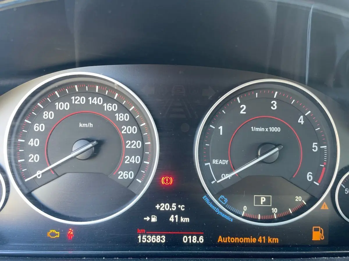 Tableau de bord de BMW Série 3 Touring F31 blanc, vue rapprochée des compteurs avec affichage digital et voyants allumés.