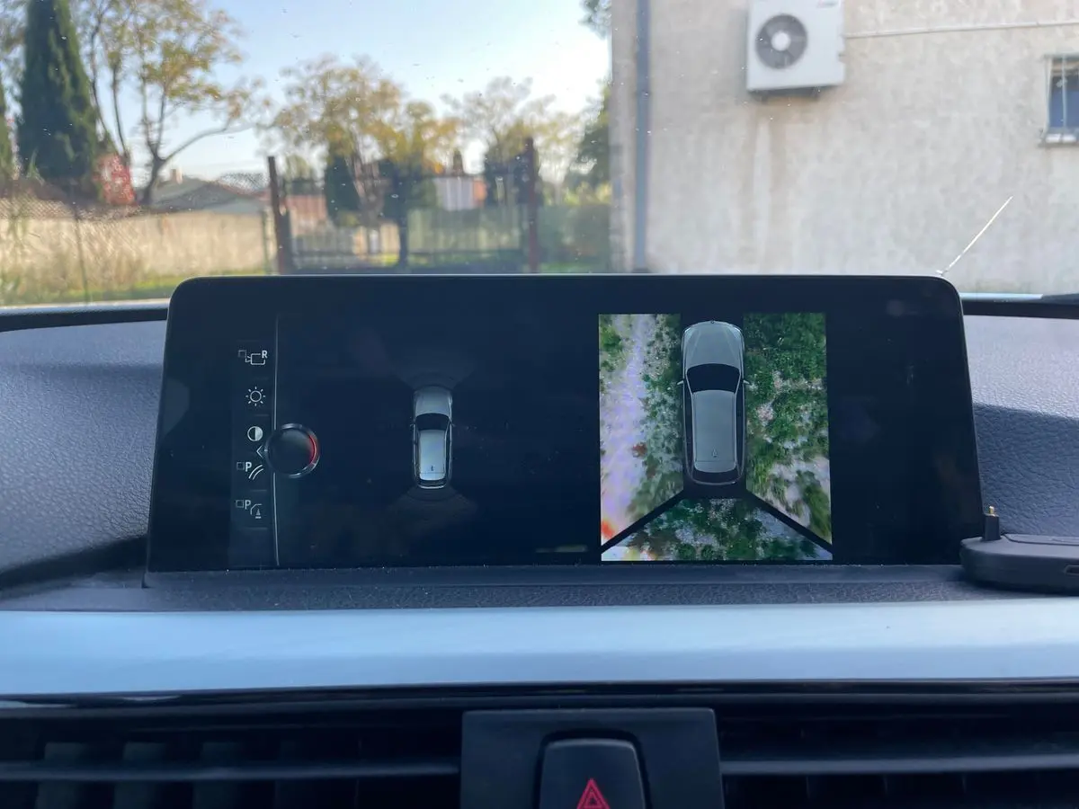 Écran de bord de BMW Série 3 Touring F31 blanc montrant la vue 360° de l'environnement extérieur en stationnement.