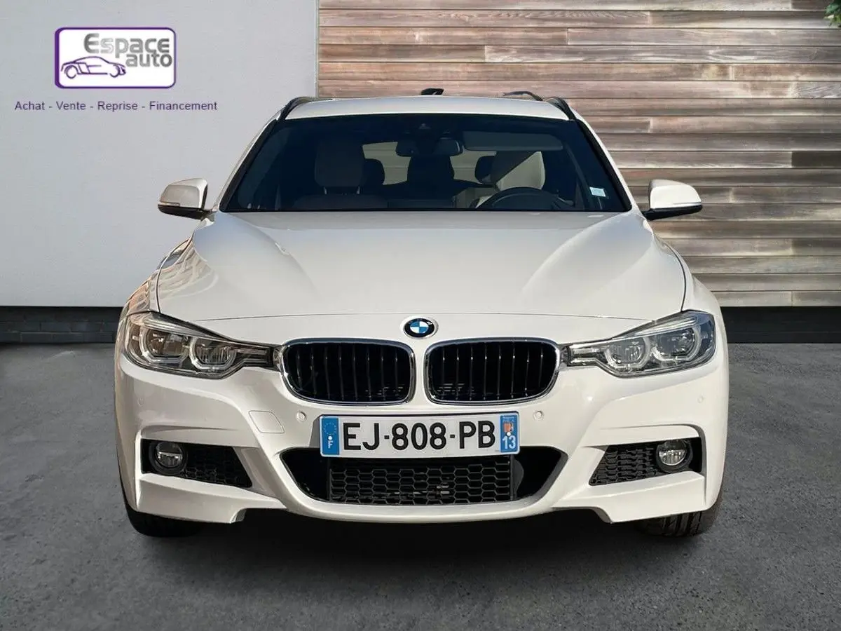 Vue frontale d'une BMW Série 3 Touring F31 blanche de 2017 avec calandre noire et phares LED distinctifs.