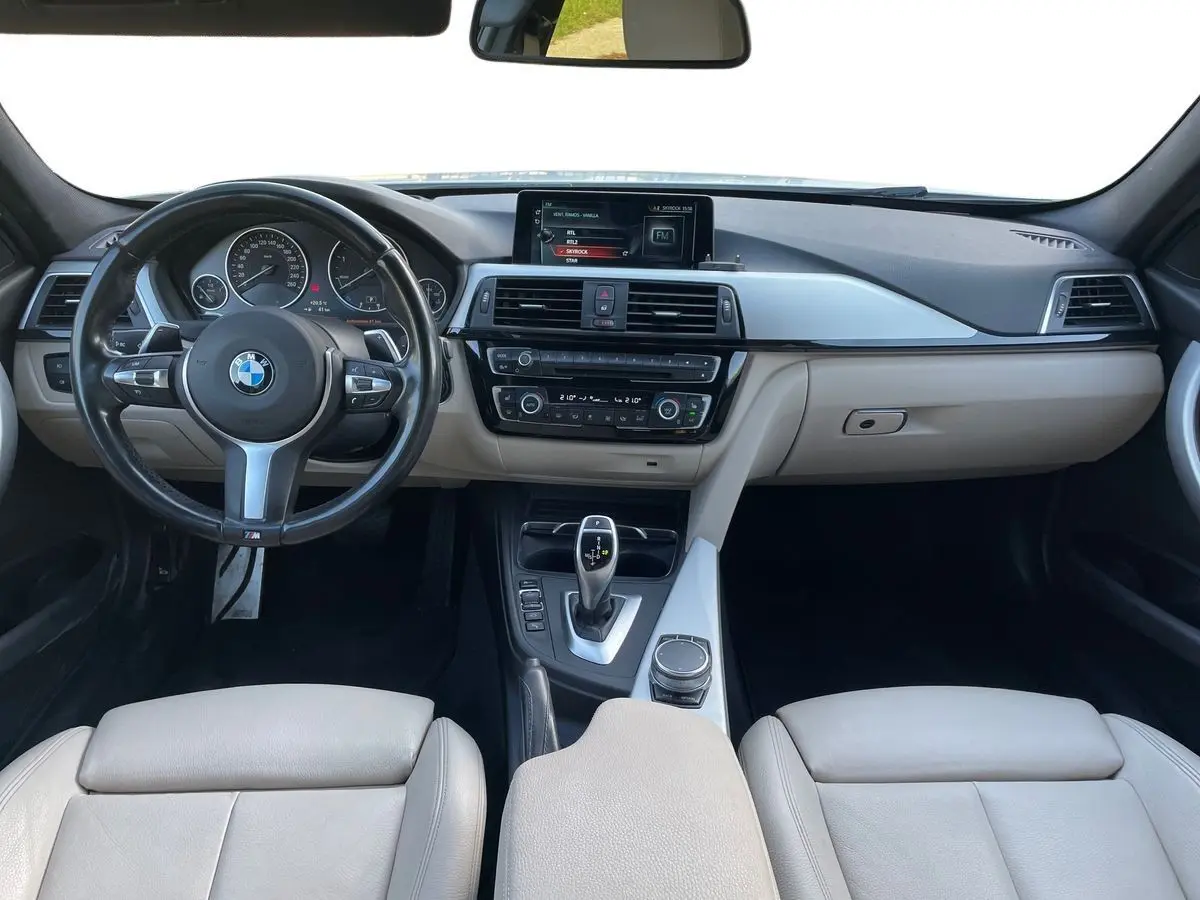 Vue intérieure avant de la BMW Série 3 Touring F31 330DA M Sport 2017 avec tableau de bord noir et sièges cuir beige.