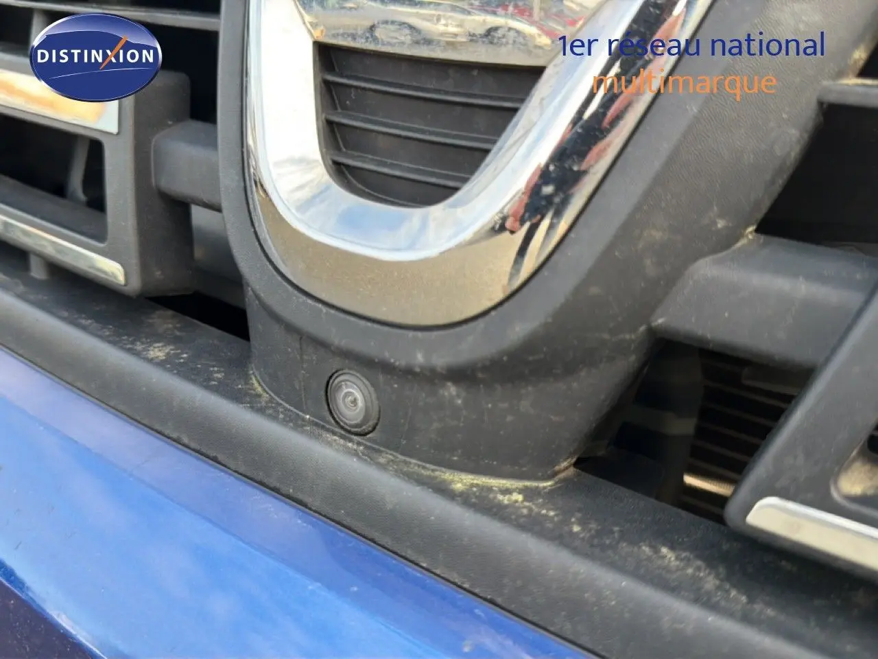 Gros plan sur la calandre avant bleu iron du Dacia Duster 2022 avec caméra de recul intégrée.